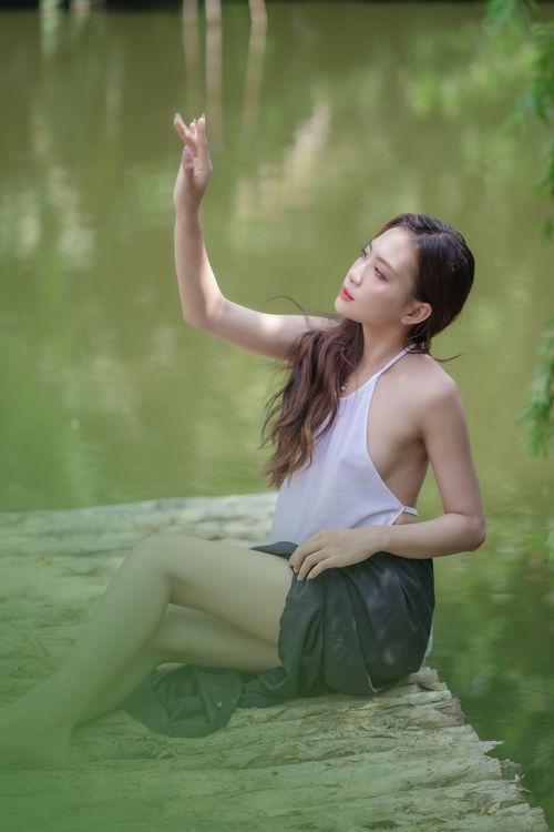 Free A woman sits peacefully by a serene lake, enjoying the spring light and natural beauty. Stock Photo