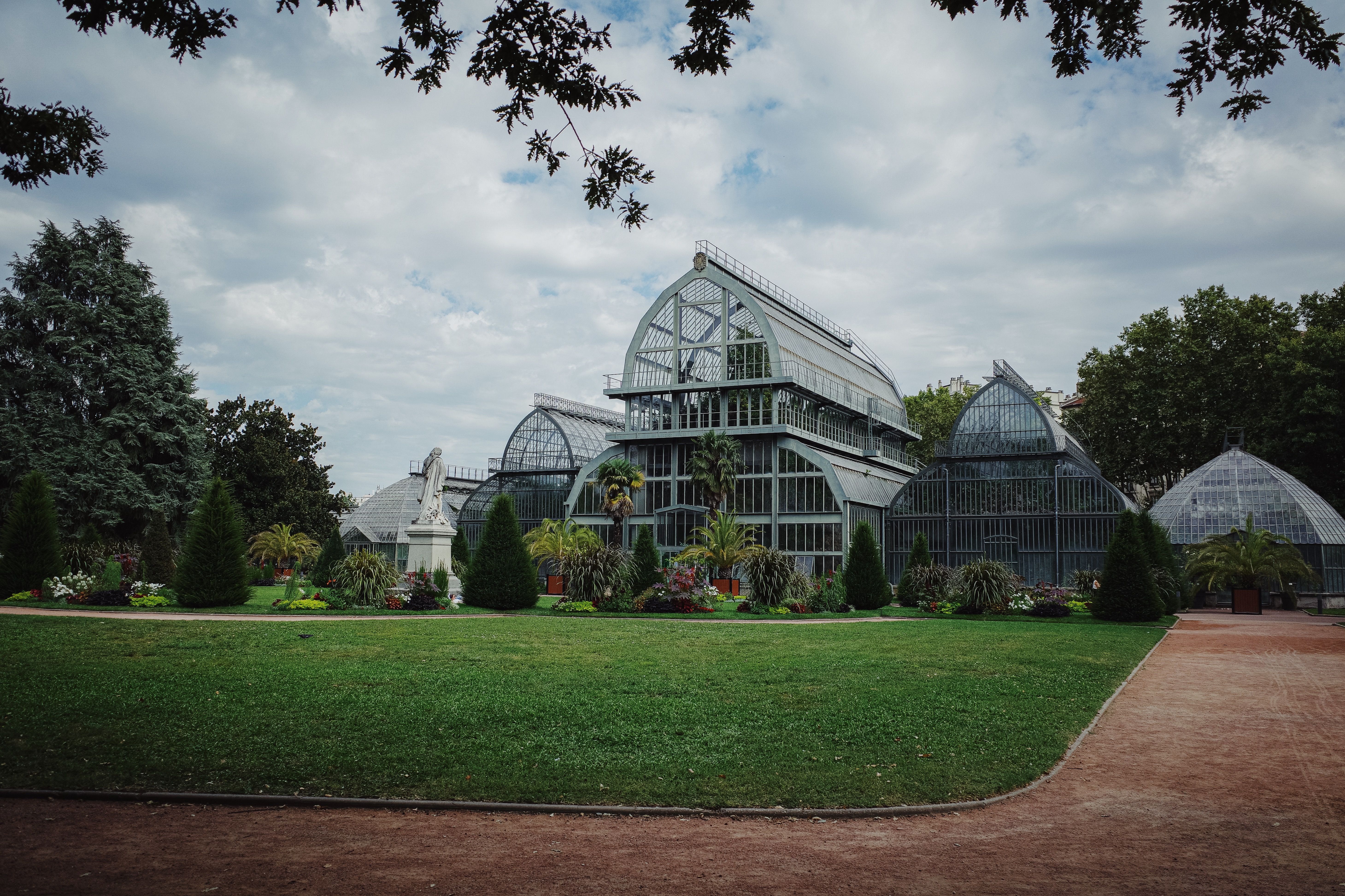 Elegant greenhouse architecture surrounded by lush greenery in a botanical garden setting.