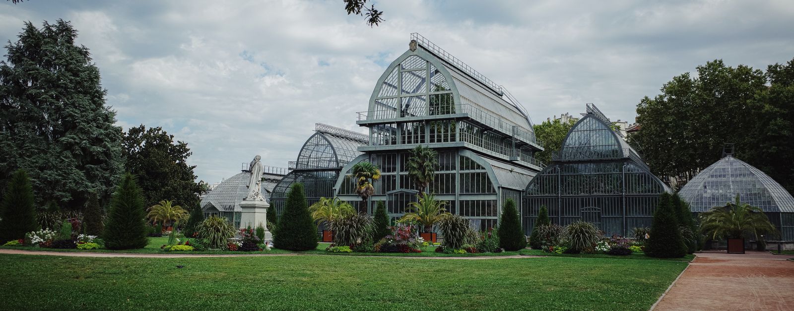 Elegant greenhouse architecture surrounded by lush greenery in a botanical garden setting.