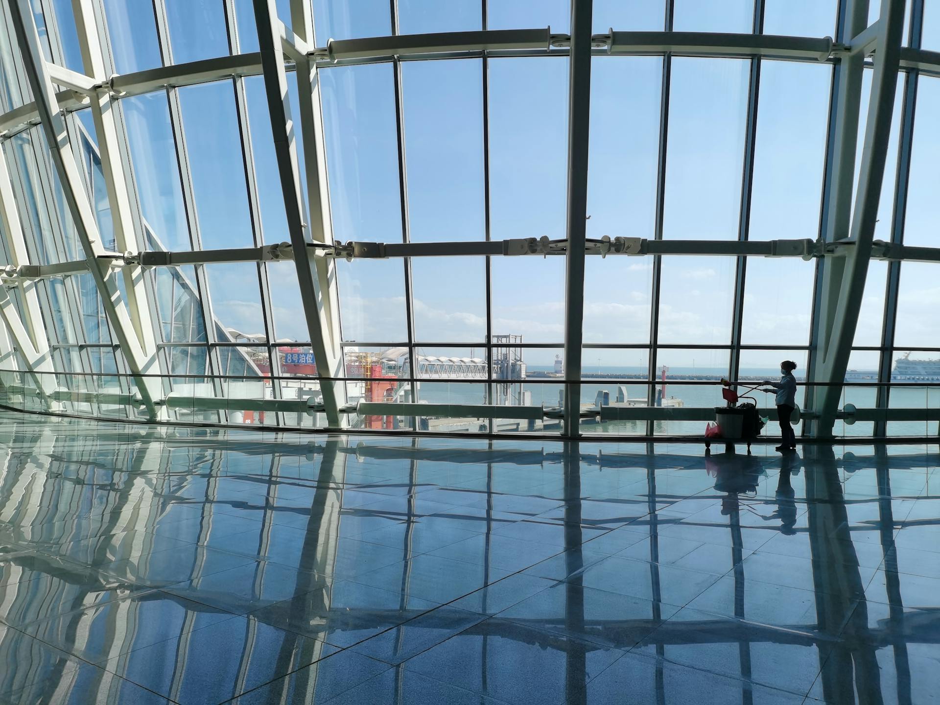 A spacious harbor terminal with large reflective windows overlooking the sea.