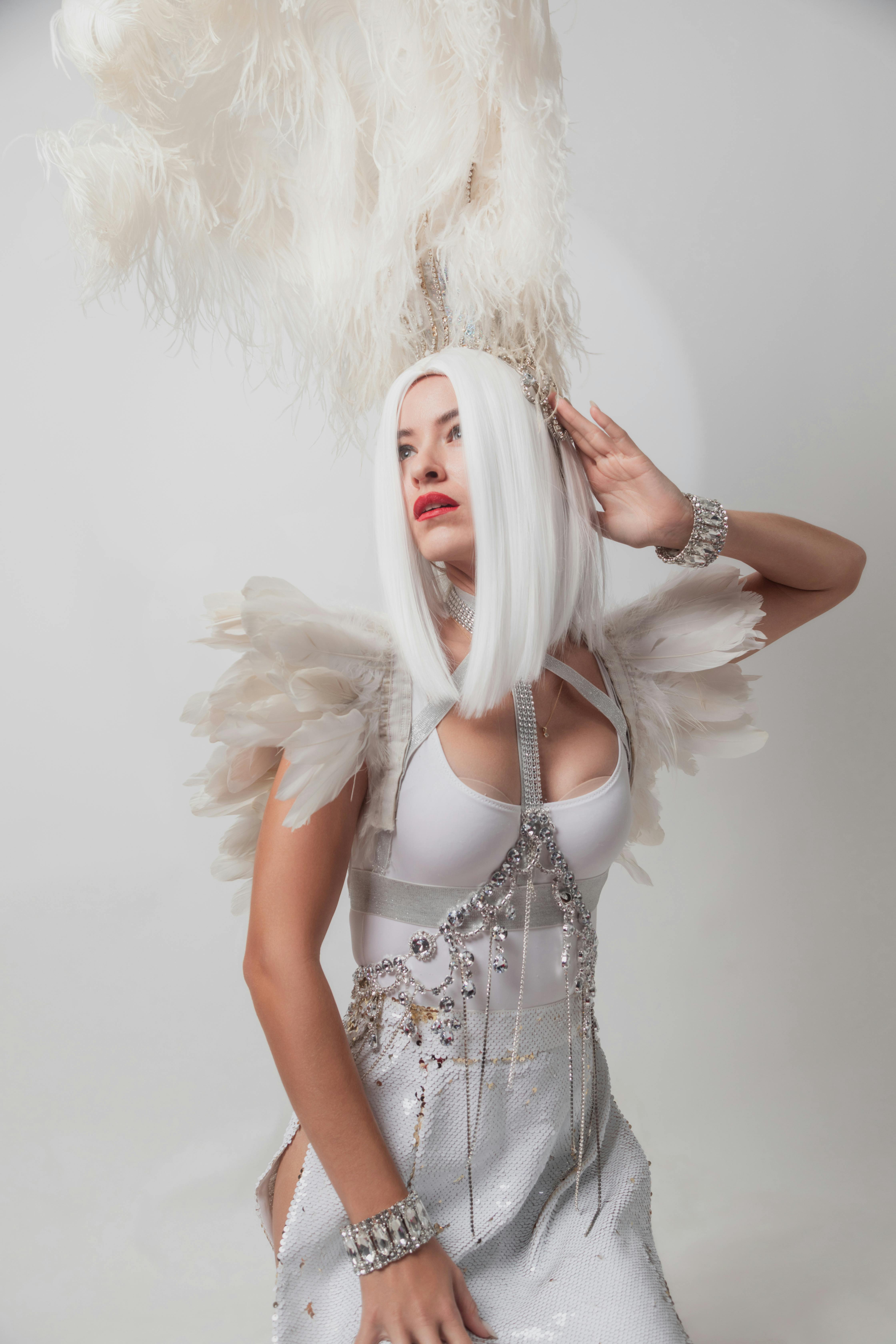 woman posing in a white costume with feathers