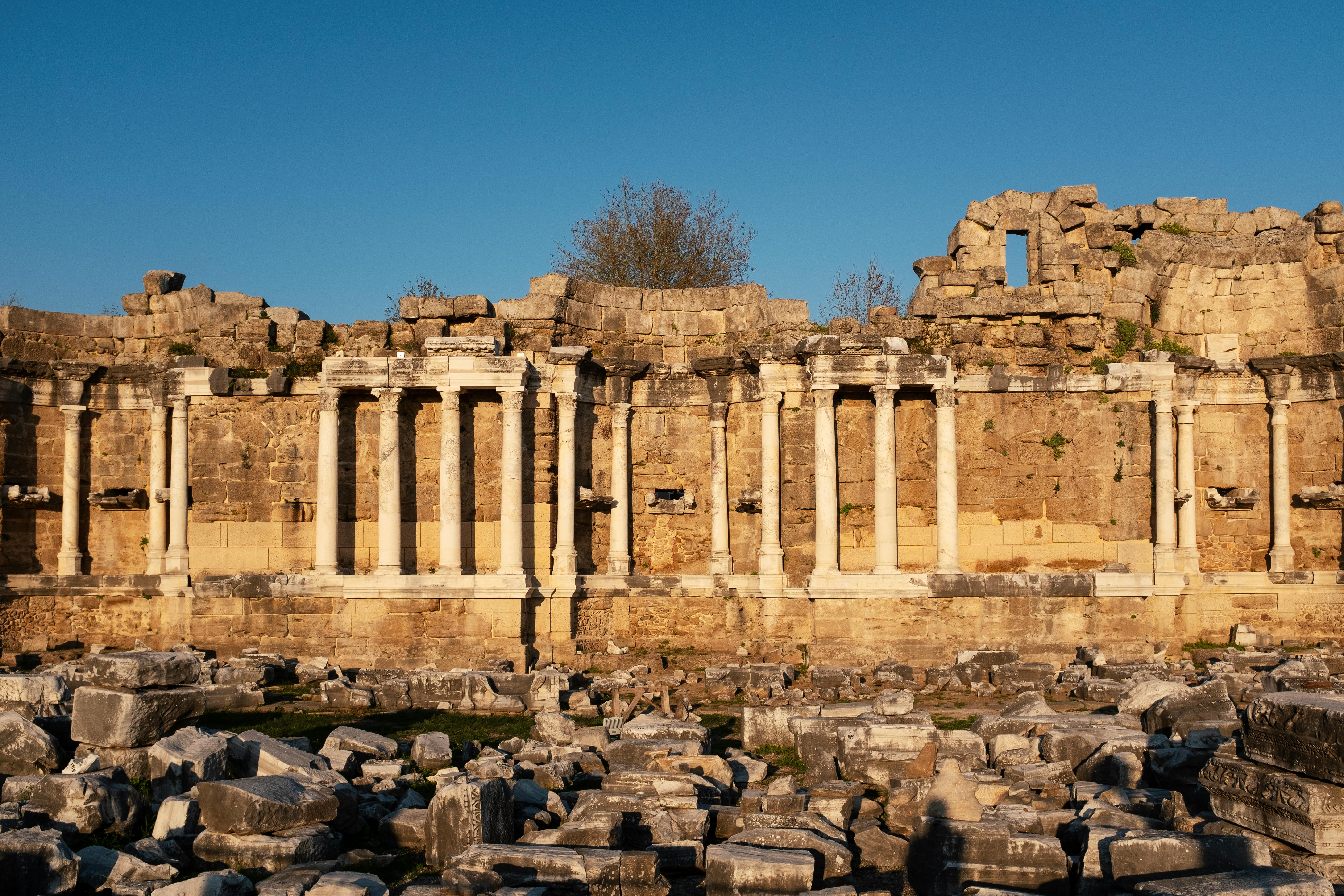 Explore the majestic ancient Roman ruins in Side, Antalya, Türkiye, bathed in golden sunset light.