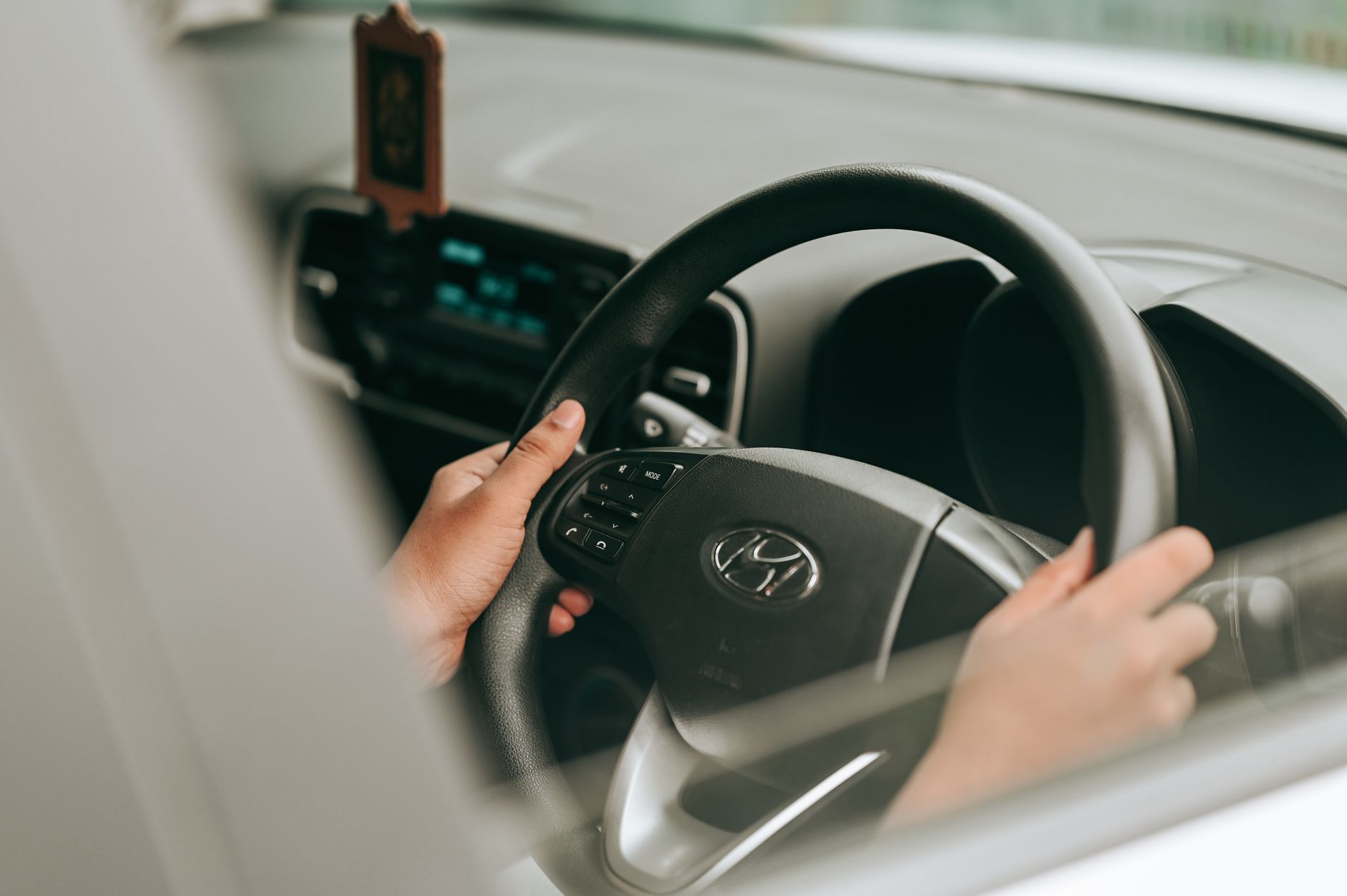 Close-up view of hands holding the steering wheel inside a car.