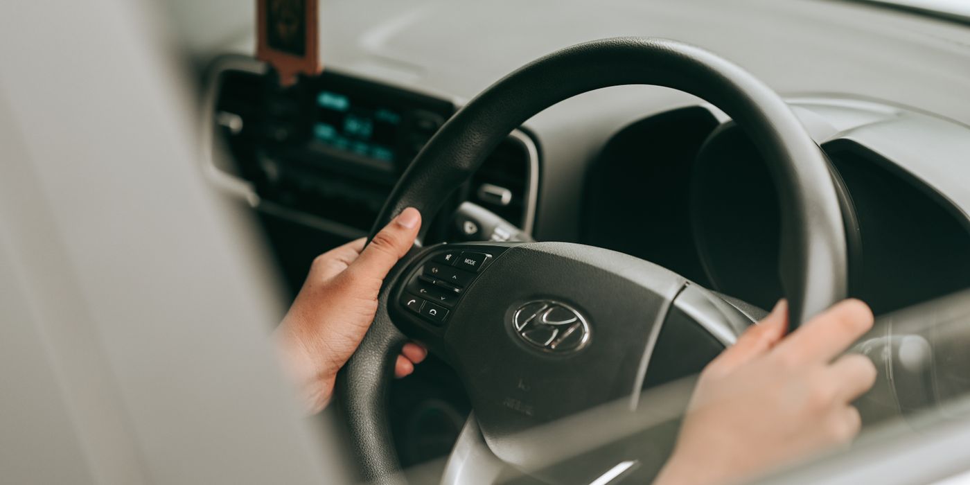 Close-up view of hands holding the steering wheel inside a car.