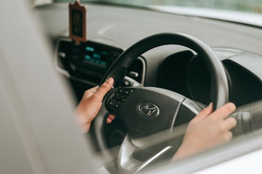 Close-up view of hands holding the steering wheel inside a car.