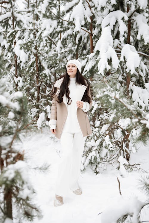 Young Brunette Standing between Snowy Trees