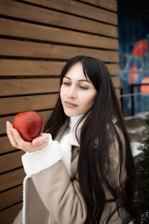Young Woman in a Jacket Holing a Red Apple