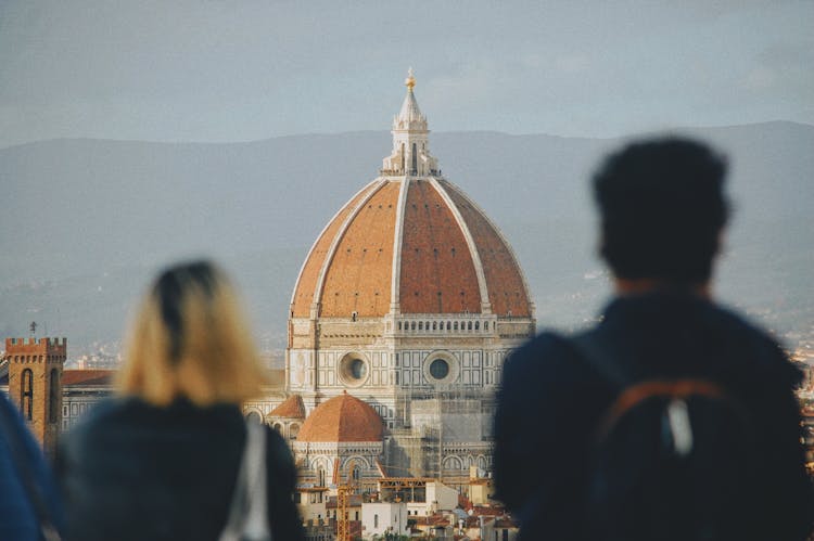 Back View Of People Standing And Looking At The Santa Maria Del Fiore Cathedral In Florence, Italy 