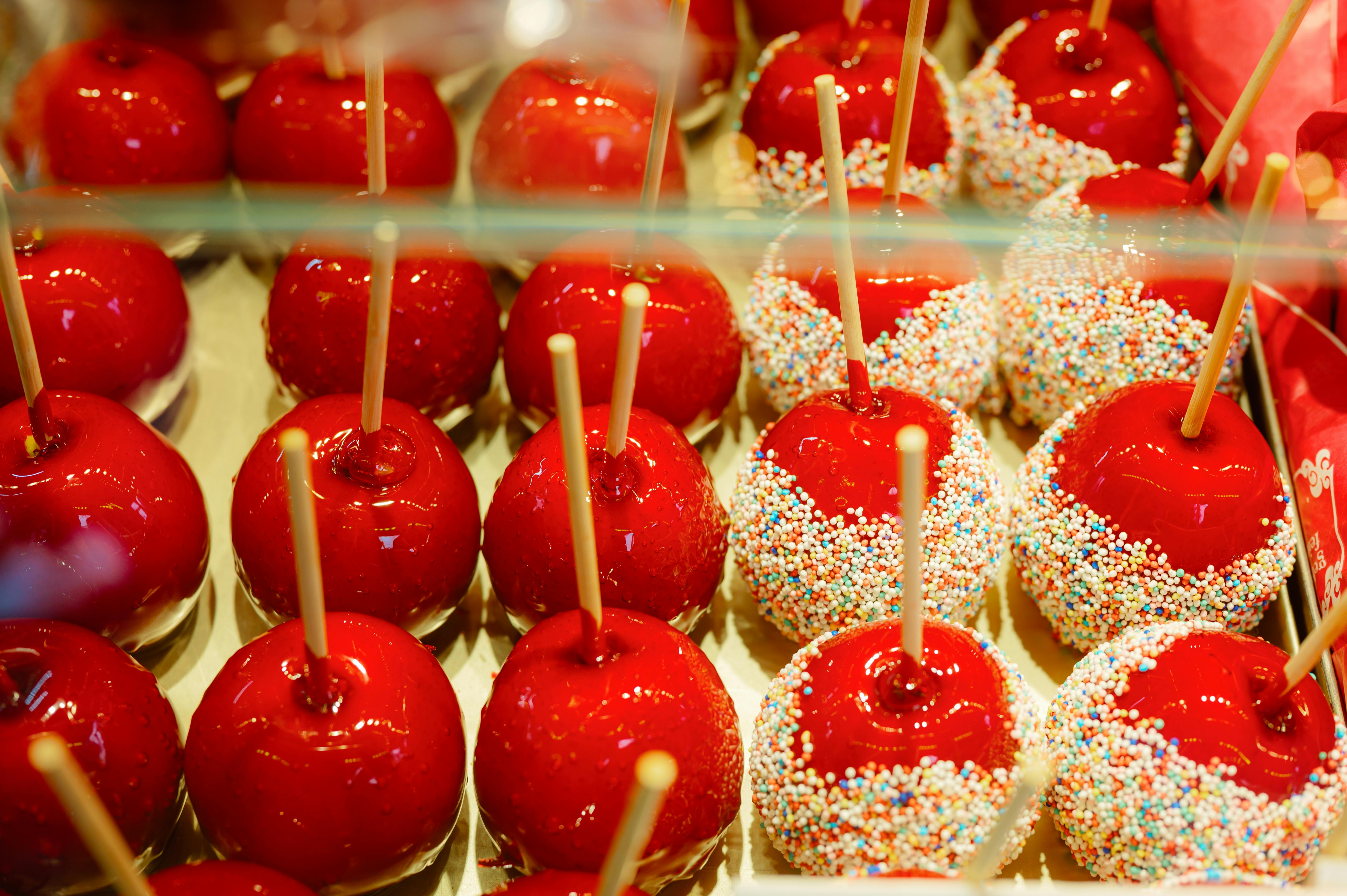 Bright red candy apples with colorful sprinkles on display, perfect for desserts.