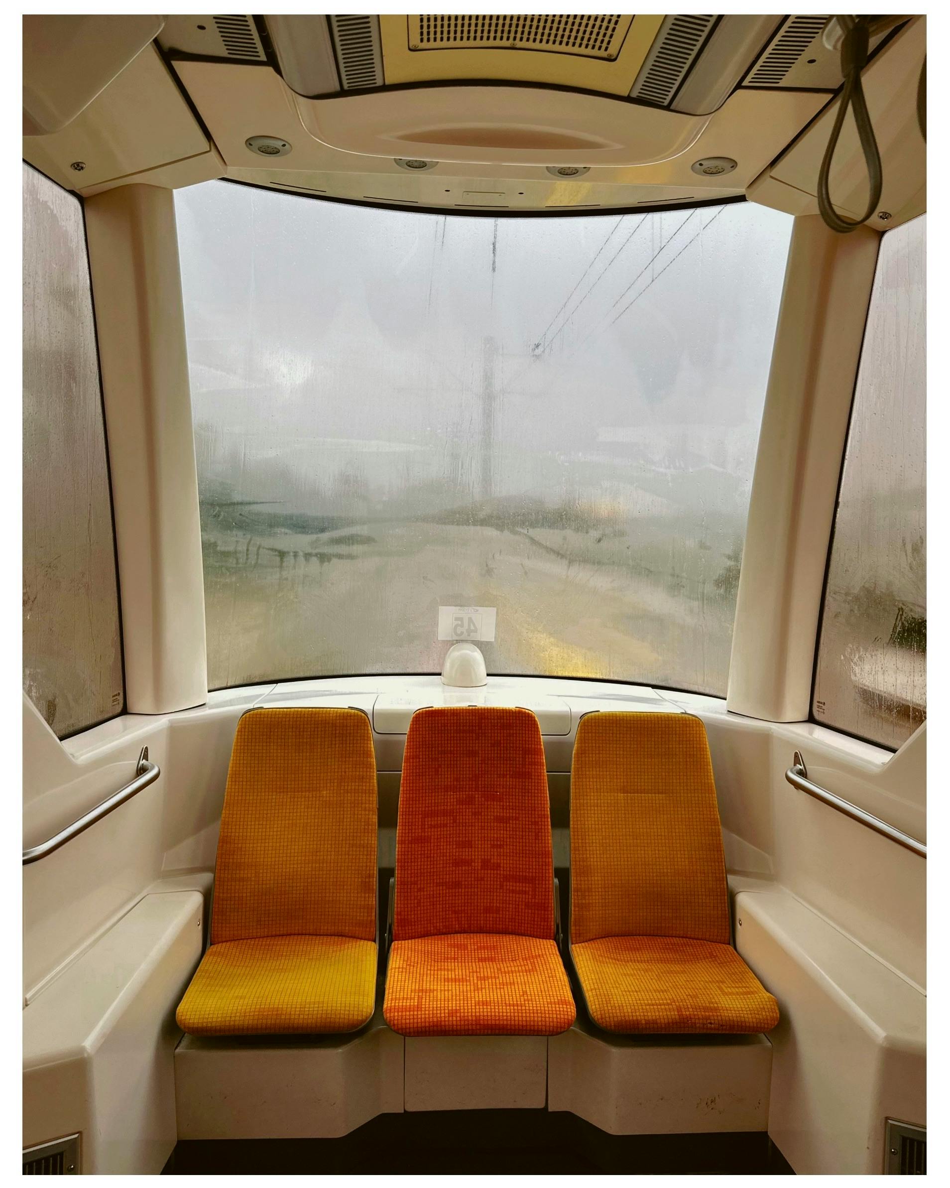 Warm and cozy seats inside a misty tram with large windows and vivid lighting.