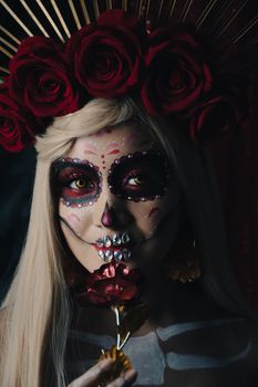 Striking portrait of a woman in Dia de los Muertos makeup with red roses.