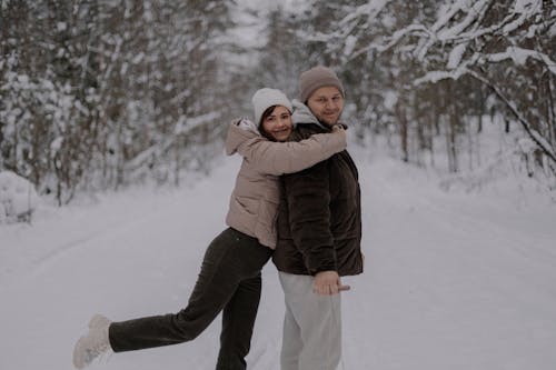 Woman Hugging Man in Forest in Winter