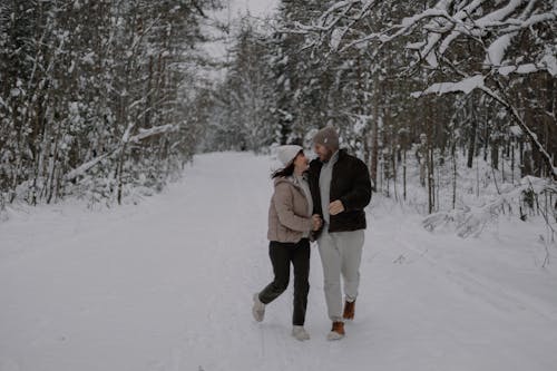Smiling Couple Walking Together in Forest in Winter