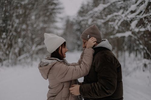 Free A joyful couple in winter attire sharing a playful moment in a snowy forest setting. Stock Photo