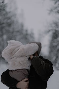 A heartwarming moment of a couple embracing in a serene winter landscape.
