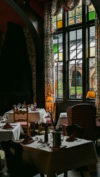 Cozy restaurant setting with elegant chairs, tables, and colorful stained glass windows.
