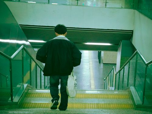 Free A man carrying a shopping bag walks down the subway stairs, back view. Stock Photo