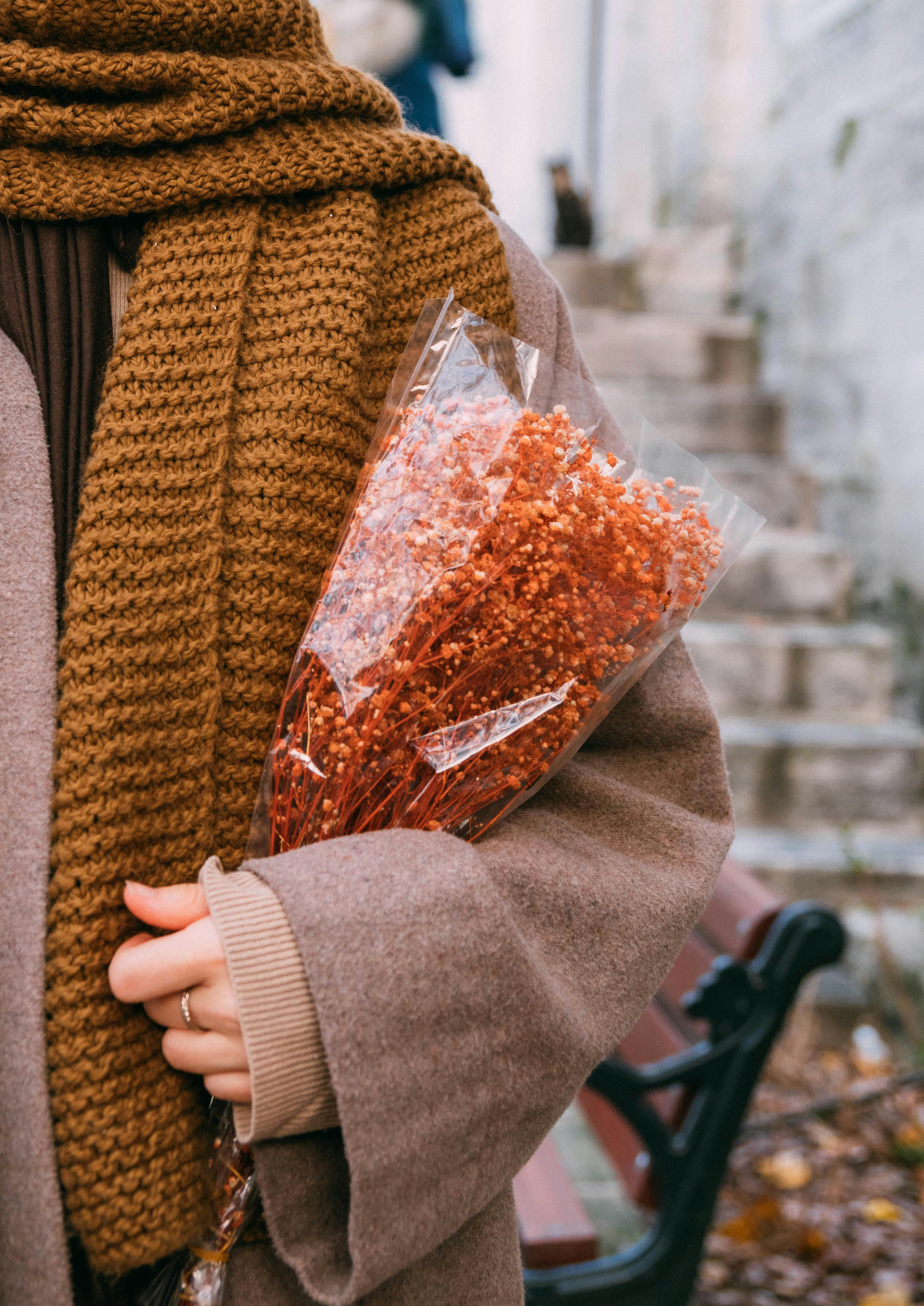 A woman in fall attire holding a dried flower bouquet on a street in İstanbul.
