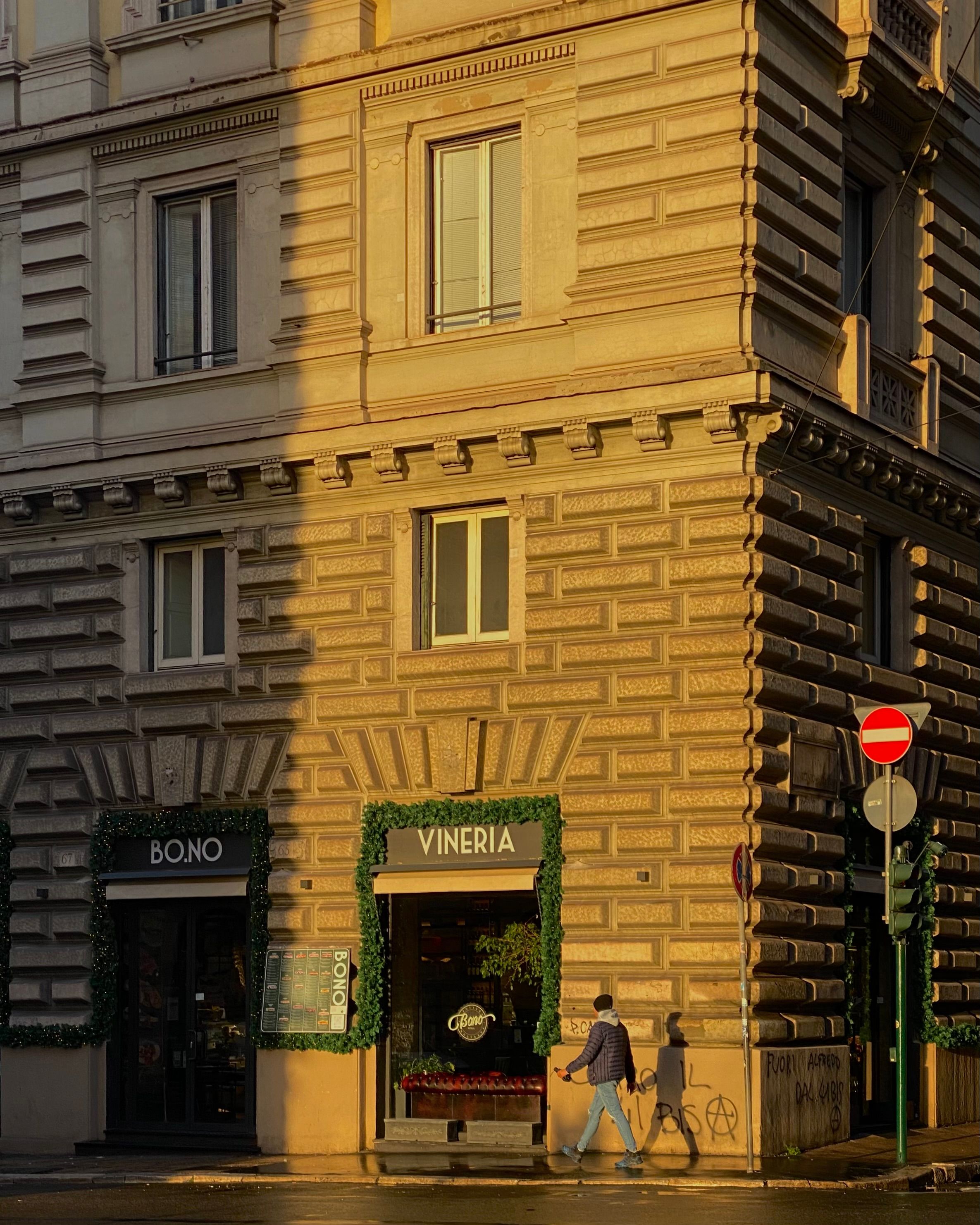 Sunlit urban building featuring charming shops Bono and Vineria in a city setting.
