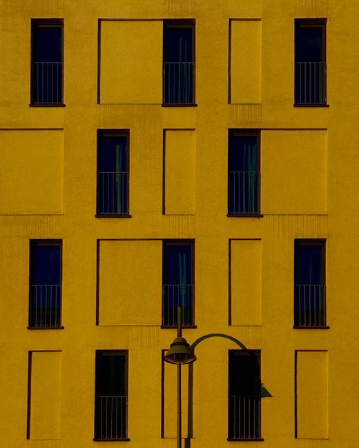 A striking yellow facade featuring symmetrical windows and minimalistic design.