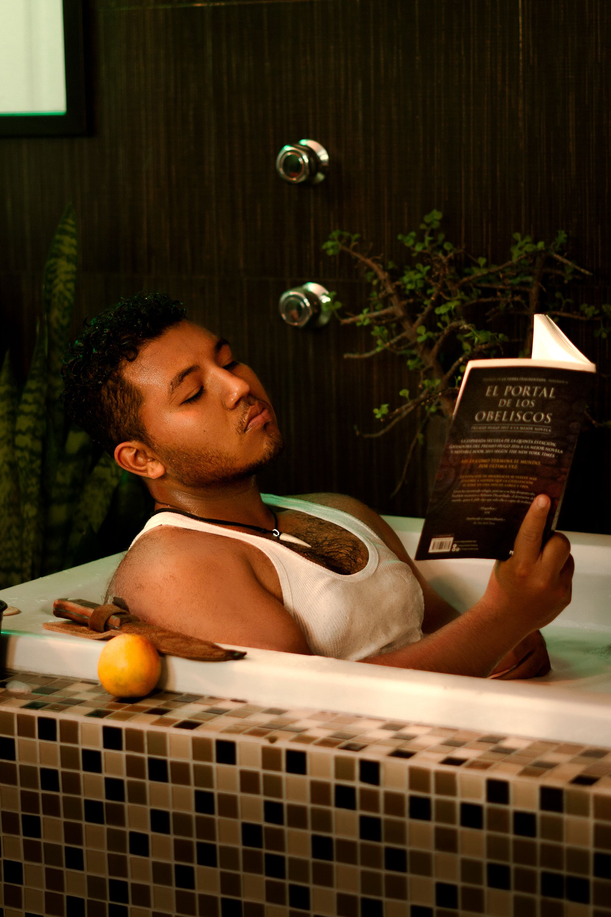 A man enjoys a peaceful moment reading in a stylish home bathtub setting.