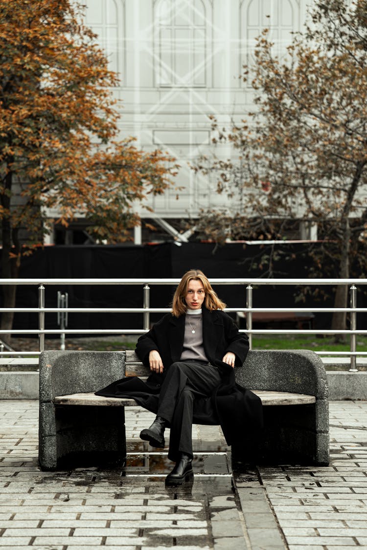 Woman Sitting On A Stone Bench On A Square 