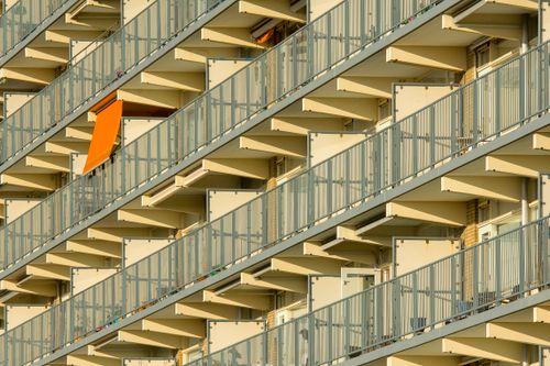 Free Diagonal view of a modern apartment building featuring balconies and a standout orange awning. Stock Photo