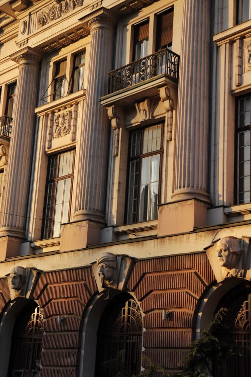 Free Elegant historic building with ornate details and large windows bathed in warm evening light. Stock Photo