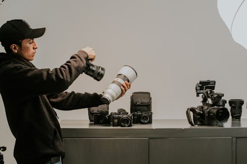 Man Holding a Professional Camera and a Lens 
