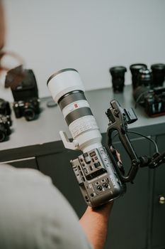 A photographer holding a high-end camera with multiple lenses in a studio setting.