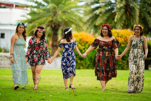 Free Group of five women walking hand in hand outdoors, wearing colorful sundresses and floral wreaths. Stock Photo
