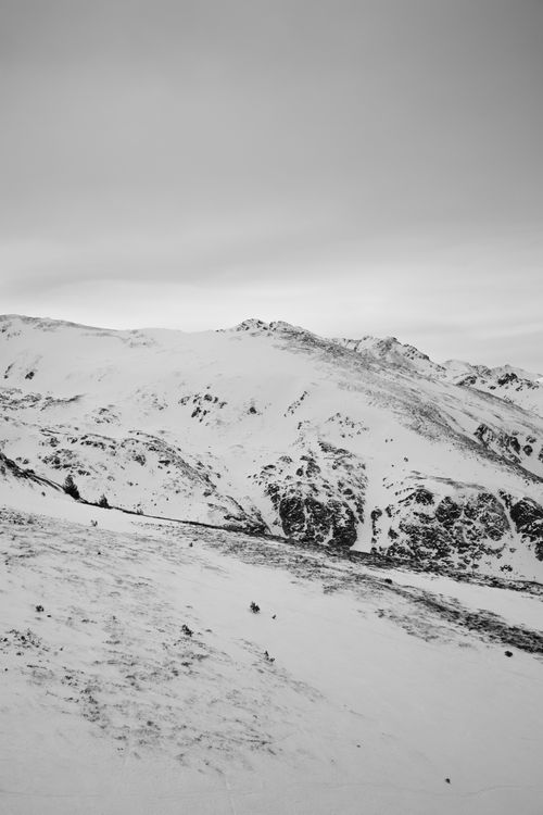 Free Black and white photo of a snow-covered mountain under an overcast sky. Stock Photo