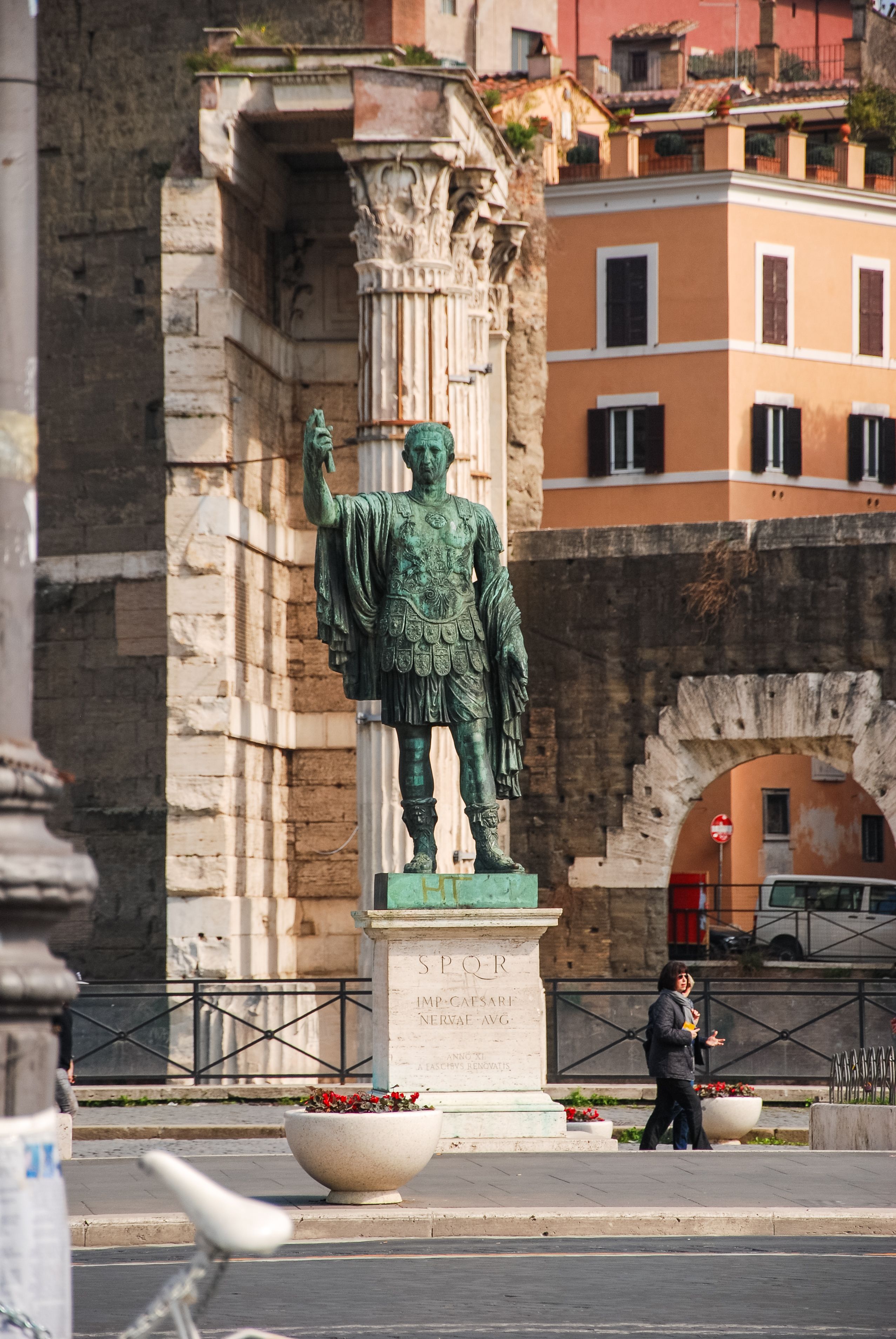 A tall statue of a Roman emperor against ancient architecture in Rome, Italy.