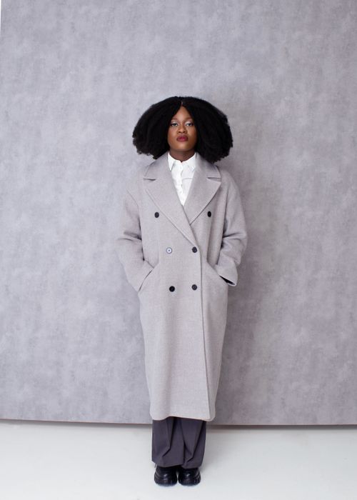 Free Elegant portrait of a woman in a stylish gray overcoat against a neutral background. Stock Photo