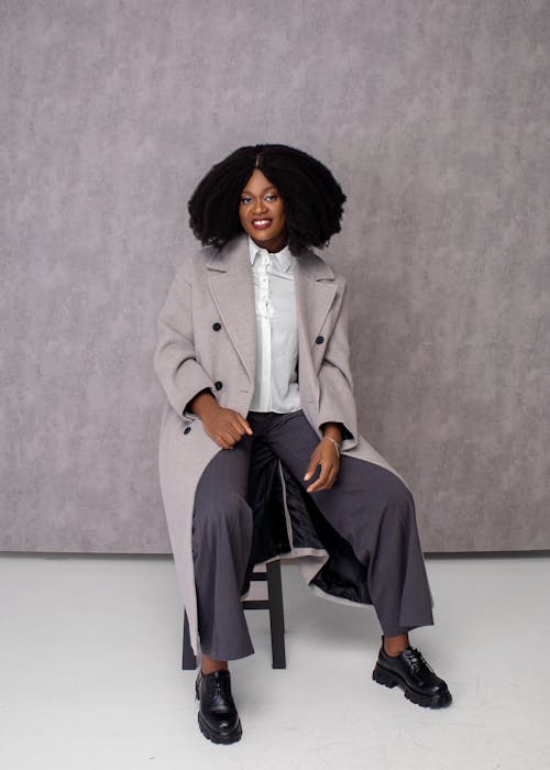 Woman in Trench Coat Sitting on Chair