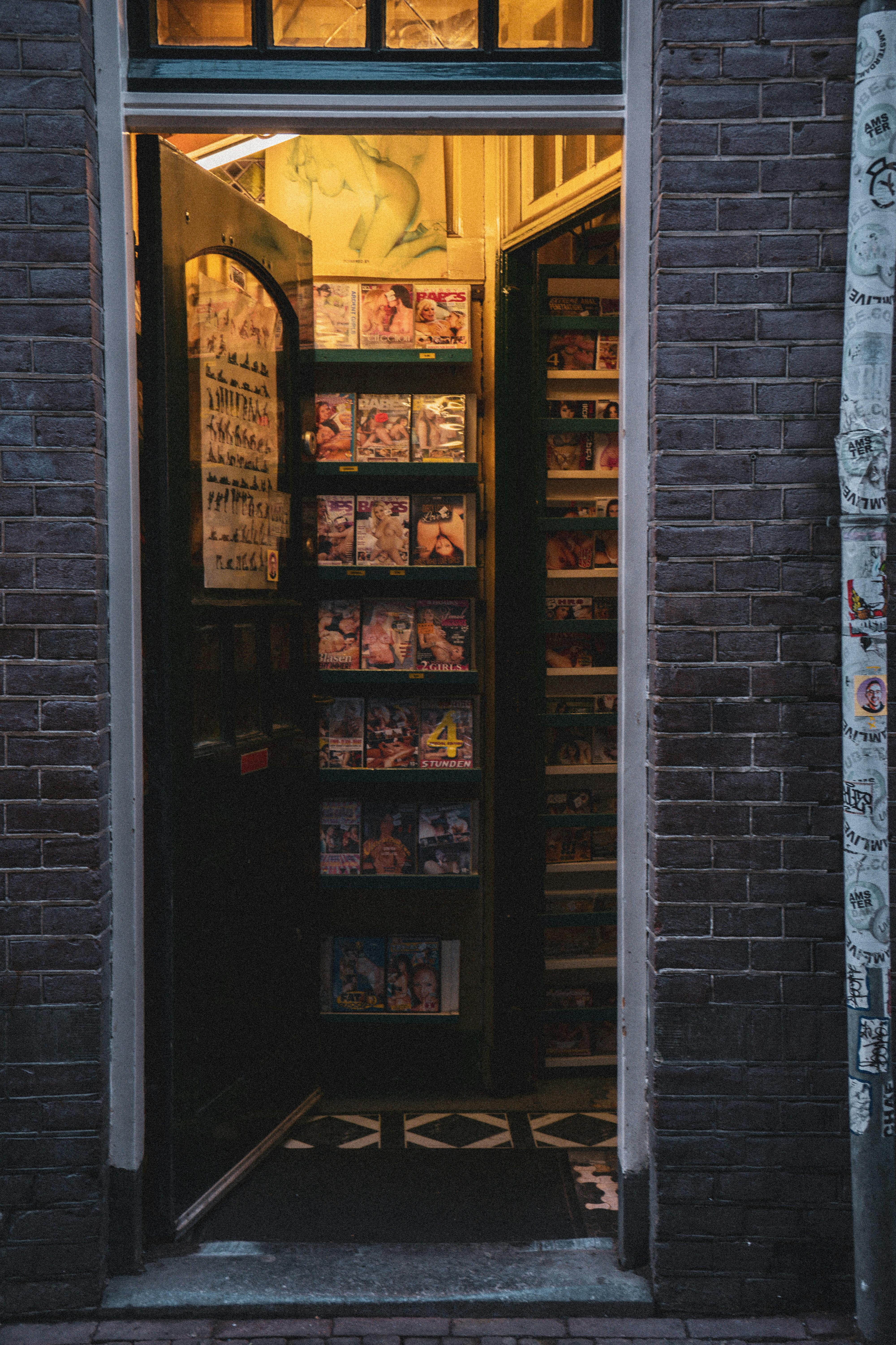 Vertical view of a boutique entrance with a warm glow, revealing shelves of merchandise inside.