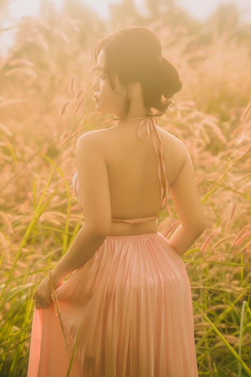 Back View of a Woman Wearing a Pink Dress, Standing in Grass