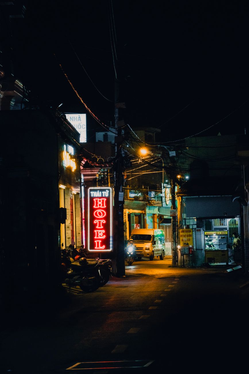 A vibrant urban street at night with neon lights and a hotel sign creating a moody atmosphere.. pexels, vibrant, urban