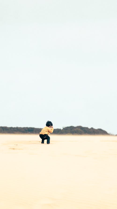 Child in Yellow Sweater on Sand