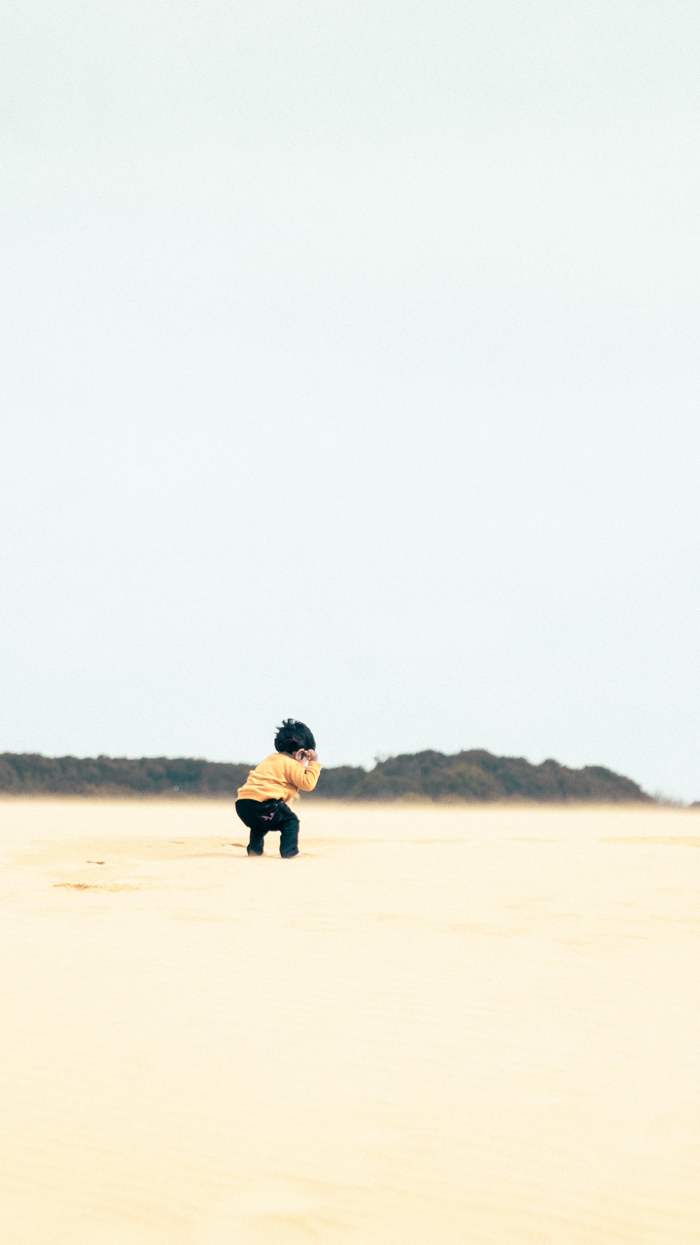 grátis Criança Com Suéter Amarelo Na Areia Foto profissional