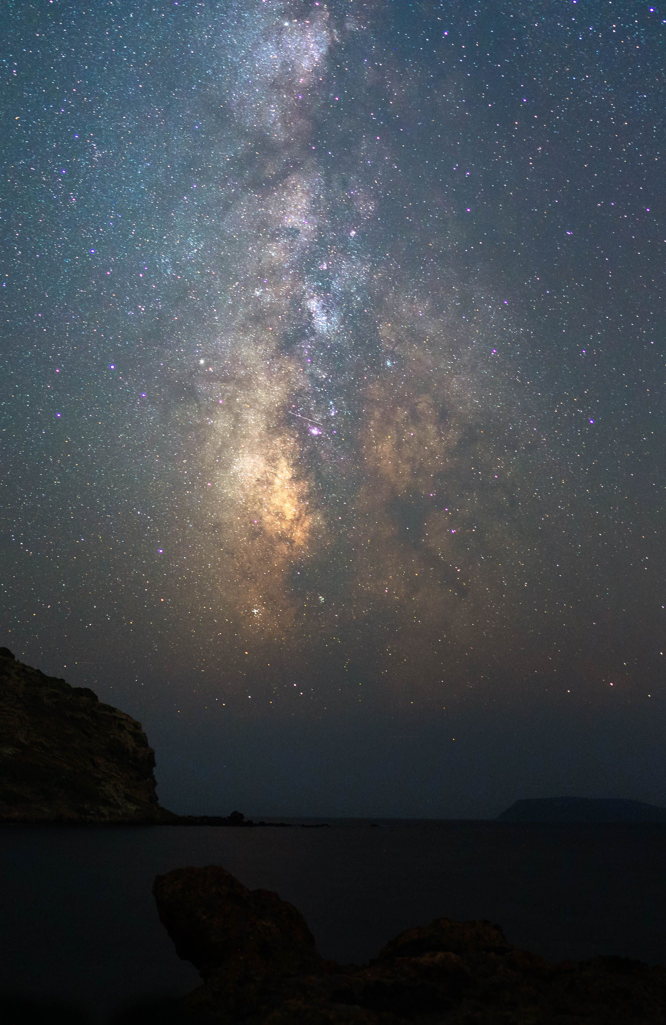 Breathtaking view of the Milky Way illuminating a serene night sky above a calm ocean shore.