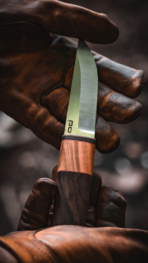 Free A detailed shot of a sharp camping knife held in leather gloves, perfect for survival and outdoor enthusiasts. Stock Photo