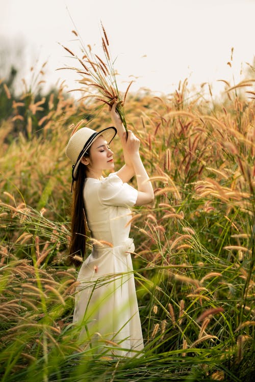 Young Woman in Sun Hat and White Summer Dress Among Desho Grass
