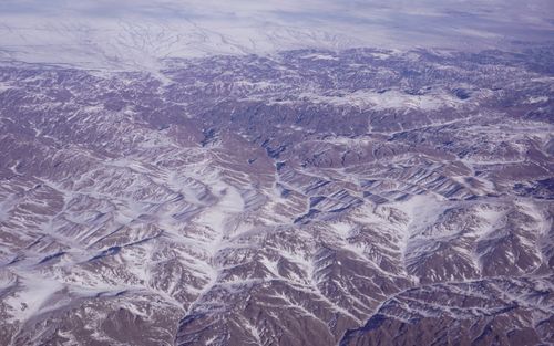 Free Aerial view of snow-dusted peaks in Xinjiang, China, showcasing winter terrain. Stock Photo