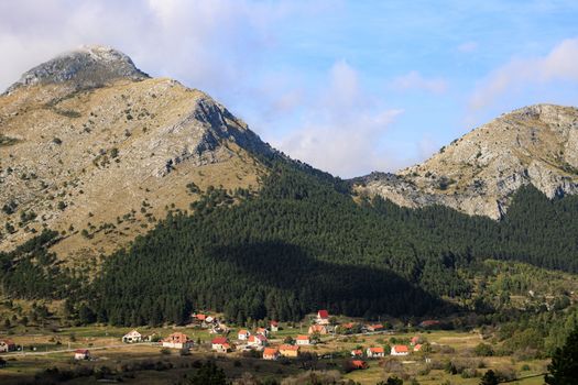 Idyllic village nestled at the foot of scenic mountains under clear blue skies.