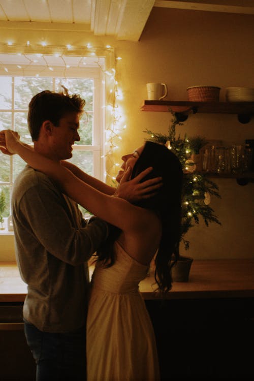 Young Couple Embracing by the Christmas Tree on the Kitchen Counter