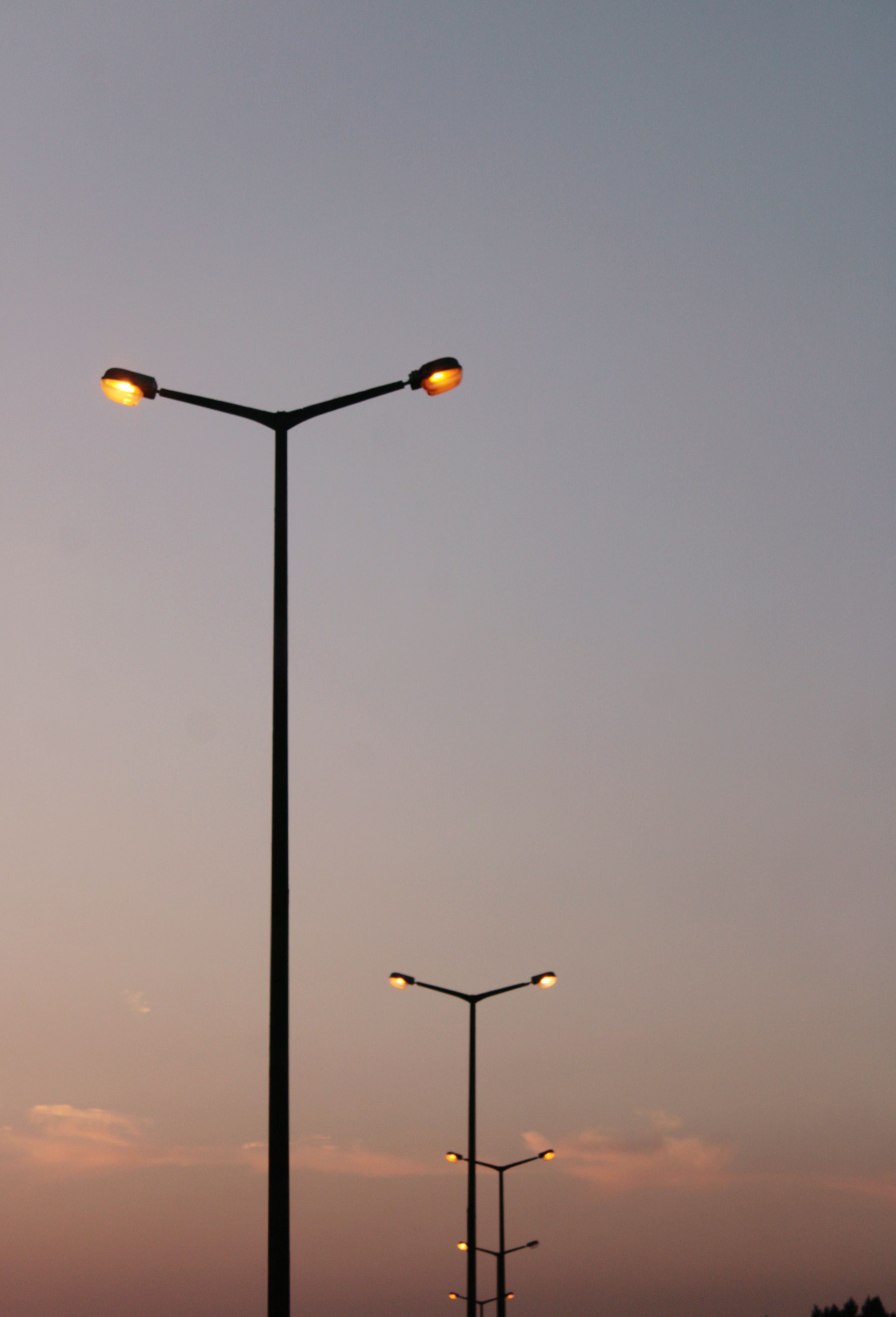 Illuminated Streetlights Against the Sky at Dusk · Free Stock Photo