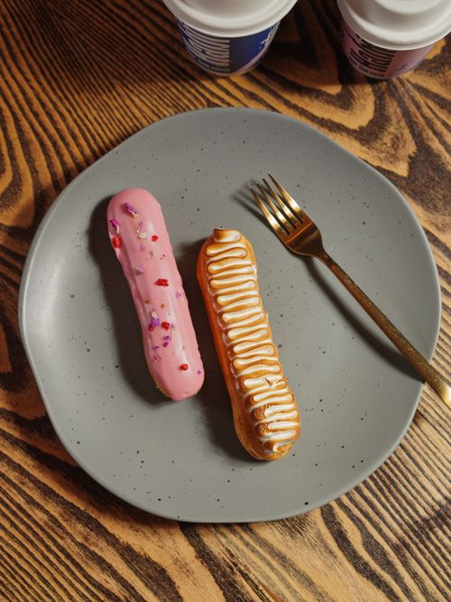 Free Delicious eclairs on a gray plate with golden fork. Perfect for dessert. Stock Photo