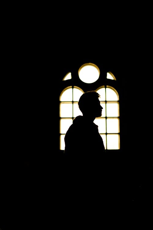 Silhouette of a Man in Front of a Church Window