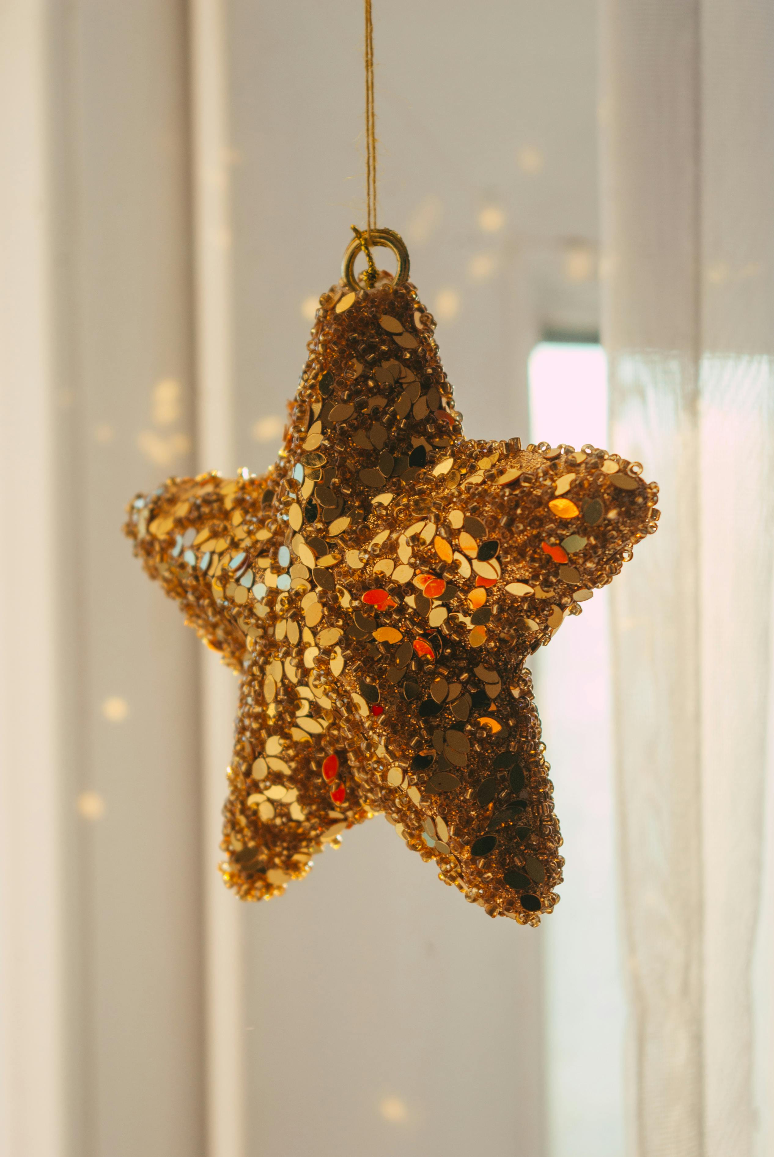 Sparkling gold star ornament hanging, perfect for holiday decoration themes.